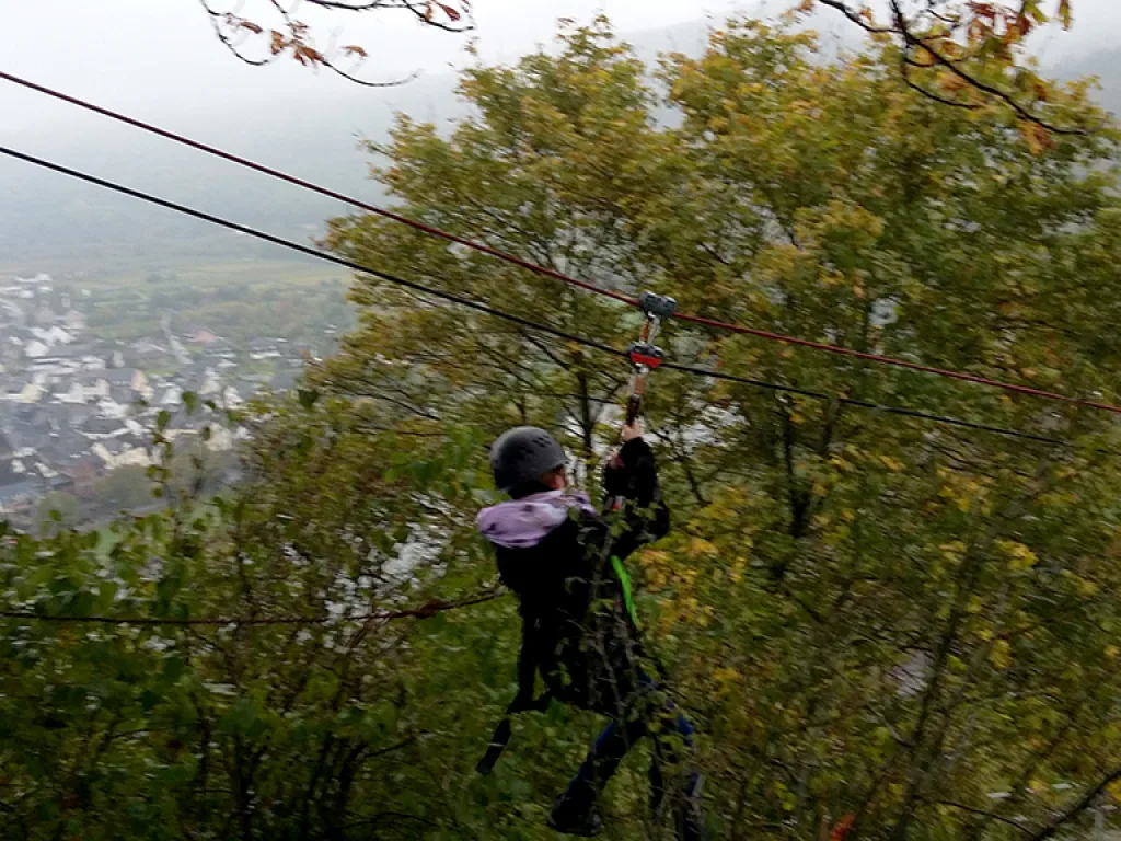 Person gleitet an der Seilrutsche über den Hang.